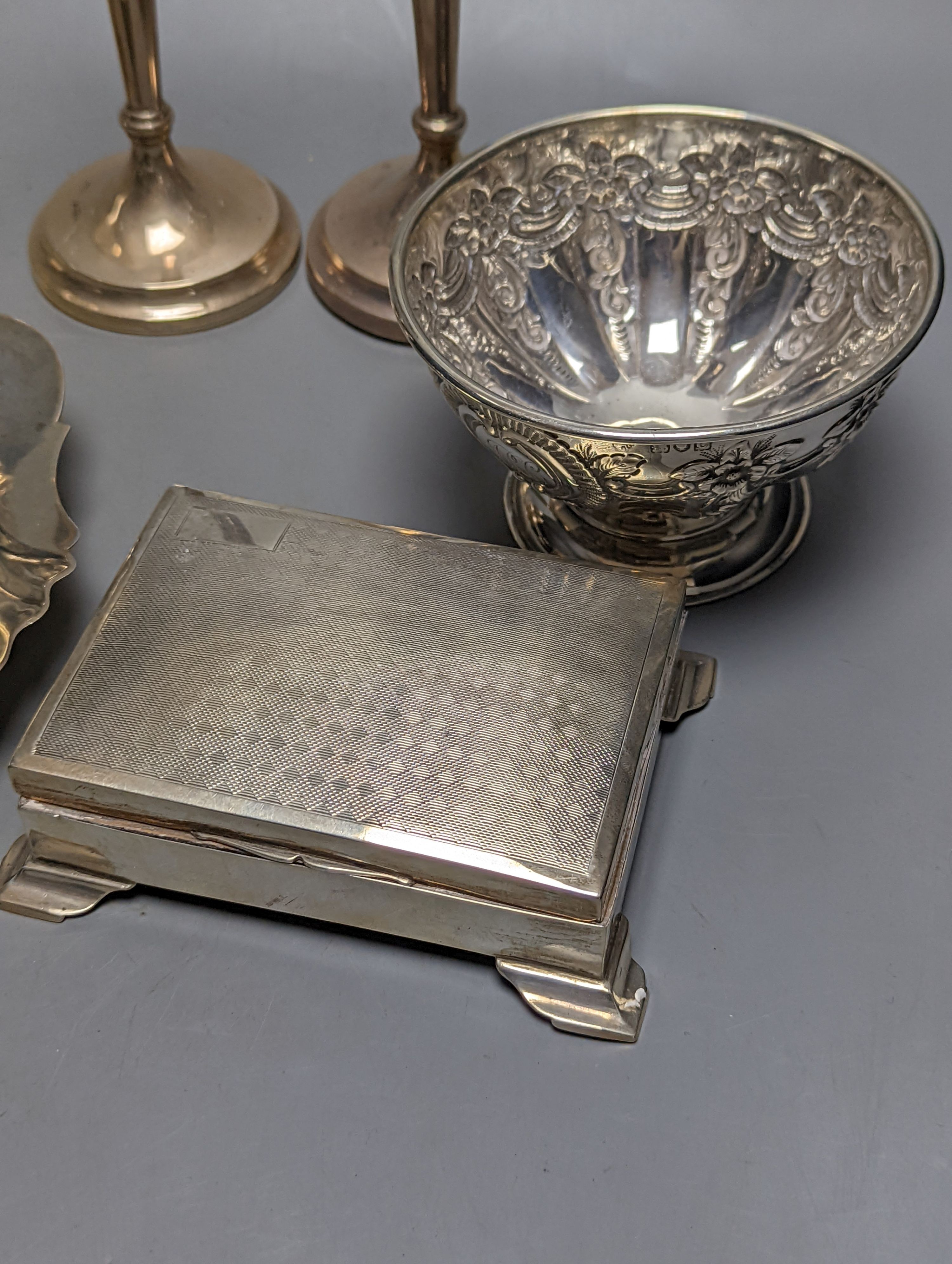 A mixed collection of silver to include a George III silver butter shell, London, 1799, a small cigarette box, two casters, a pair of slender candlesticks (loaded) and two small bowls including white metal